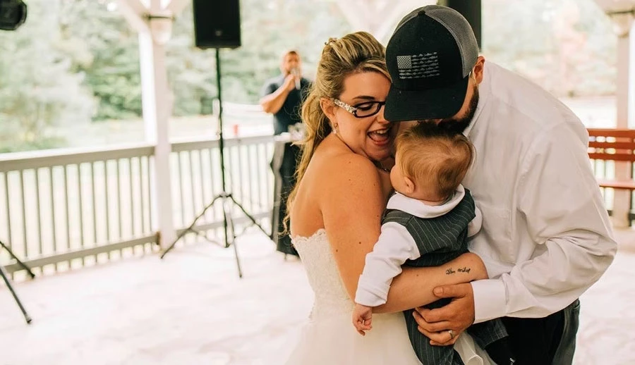 Wedding couple embracing baby on dance floor
